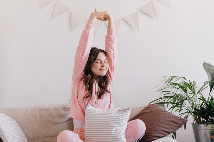 Mujer joven estirándose feliz por la mañana en casa, símbolo de una rutina matutina saludable y despertar con energía