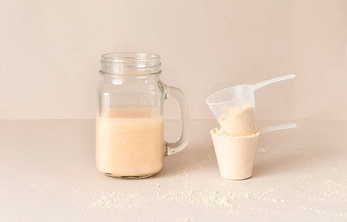 Batido de Satislent Keto en un vaso junto a un cacito con polvo